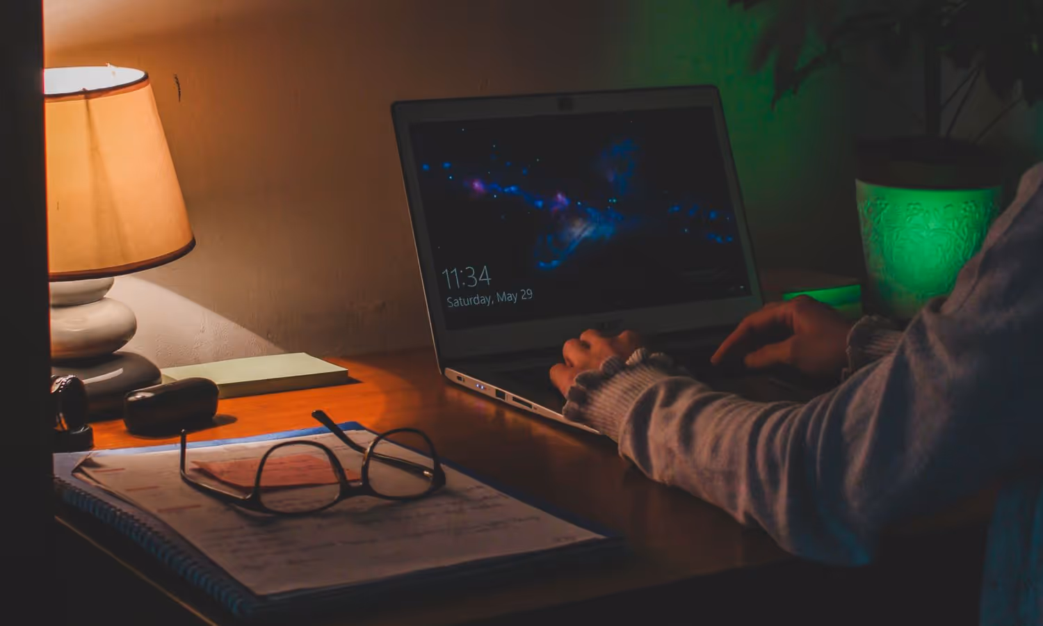 Bureau éclairé par une lampe en soirée : carnet, lunettes et échanges relus un à un