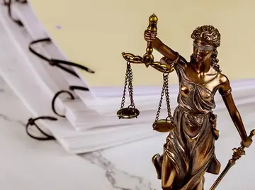 Pièces signées posées sur un bureau, près d'une figure de la justice